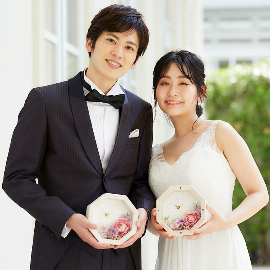 小ぶりなのにぱっと華やぐナチュラルで可愛らしいフラワーアレンジの花時計を持つ新郎新婦