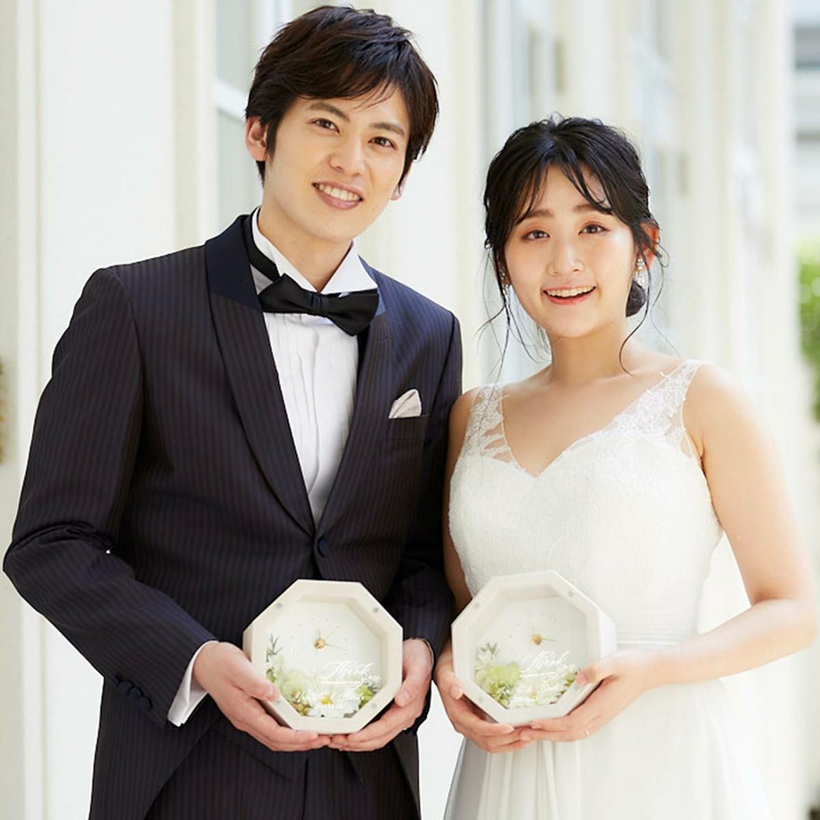 小ぶりなのにぱっと華やぐナチュラルで可愛らしいフラワーアレンジの花時計を持つ新郎新婦