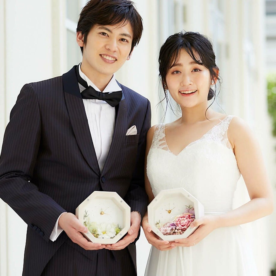 小ぶりなのにぱっと華やぐナチュラルで可愛らしいフラワーアレンジの花時計を持つ新郎新婦