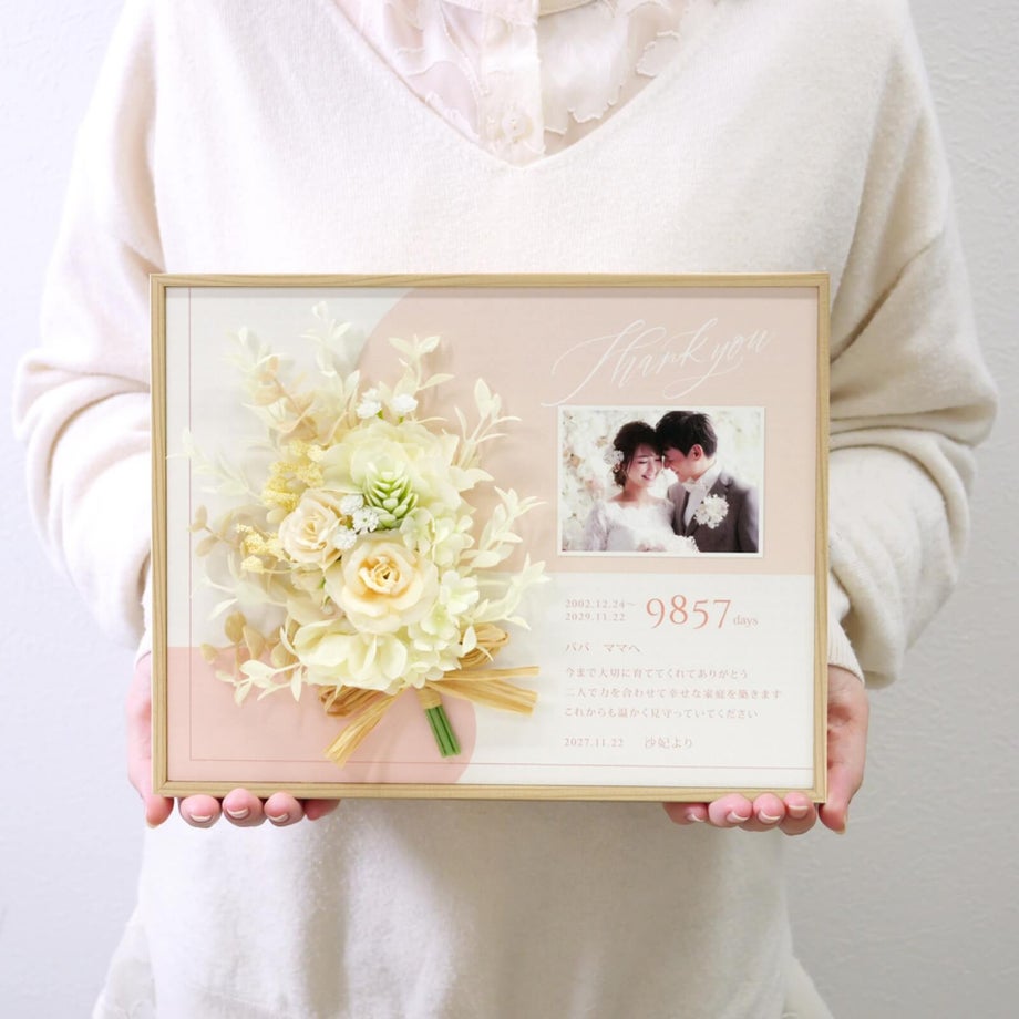 ブーケと写真で贈るナチュラルな子育て感謝状を手に持っている
